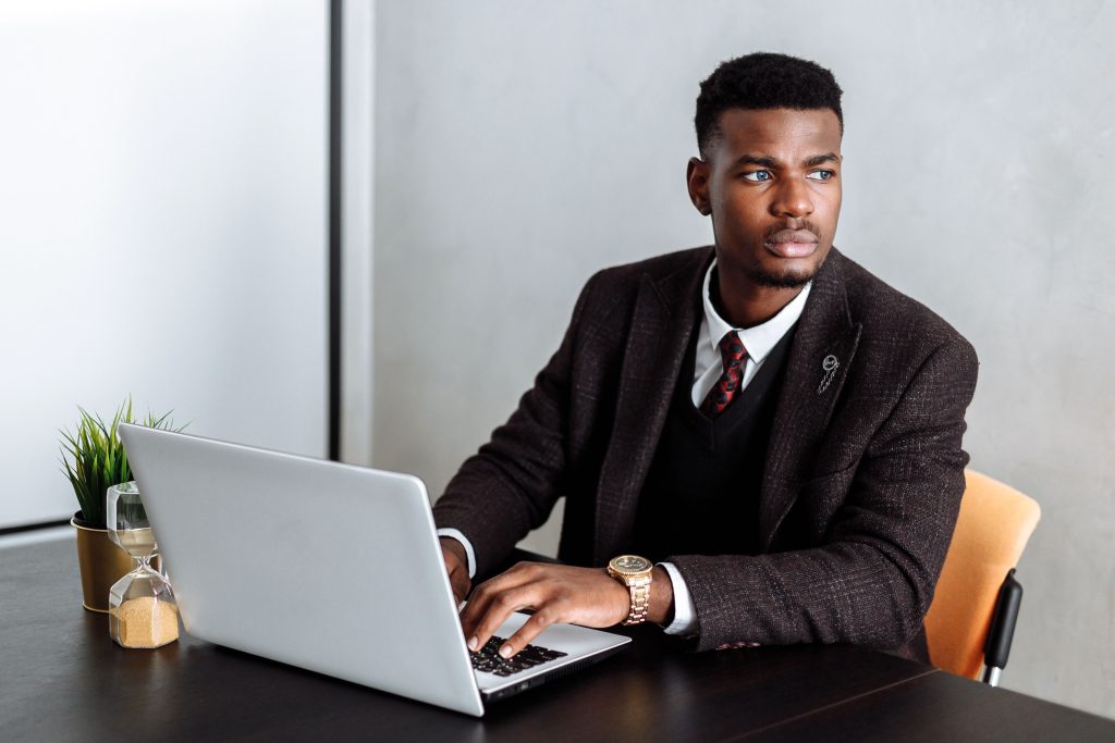 Confident businessman working on laptop at desk, focusing on tasks.